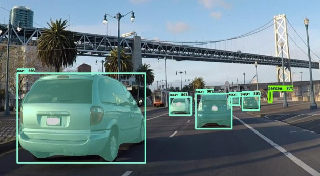 This annotated image shows a scene on the street with cars with predicted bounding boxes and instance masks generated after we run the inference.
